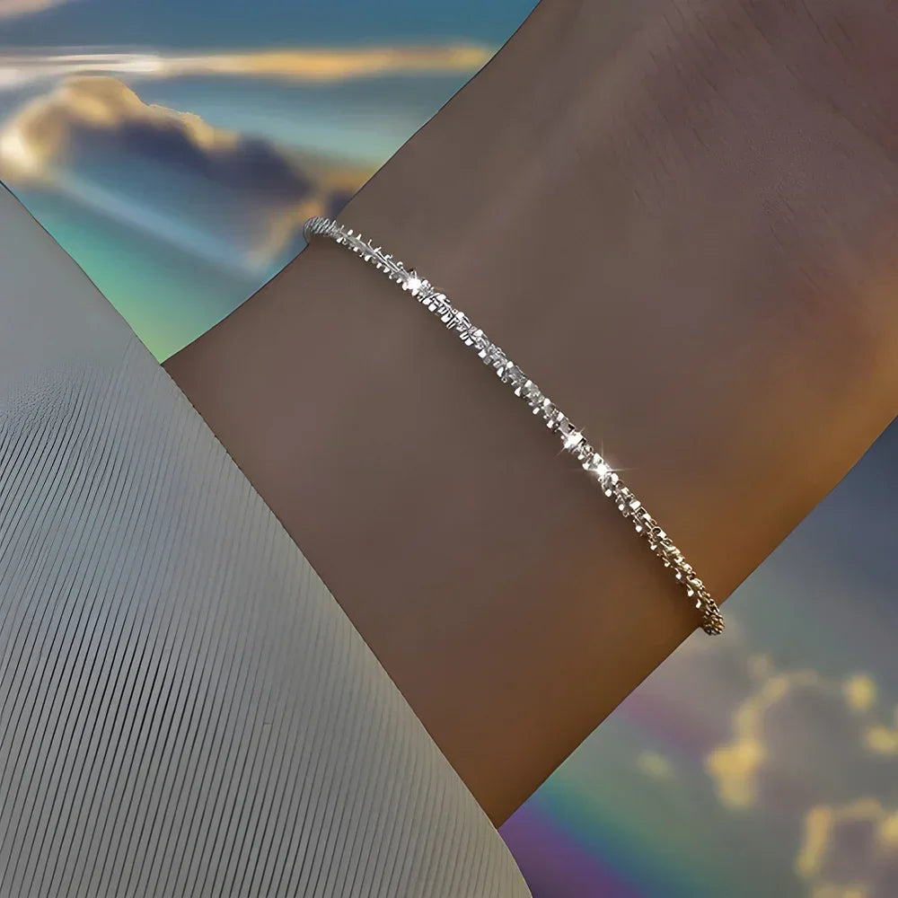 Six imitation diamond silver bracelets by Corporación Turística showcasing shiny, elegant jewelry on a neutral background.