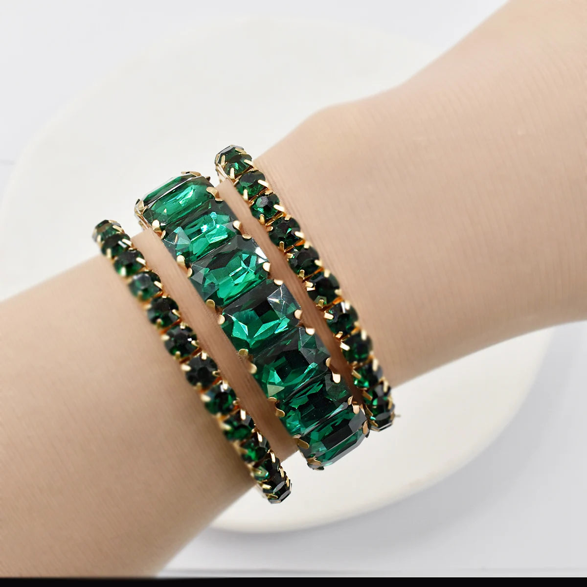 Three women's crystal gemstone bracelets with geometric designs, featuring sparkling clear and colored crystals, by Corporación Turística.