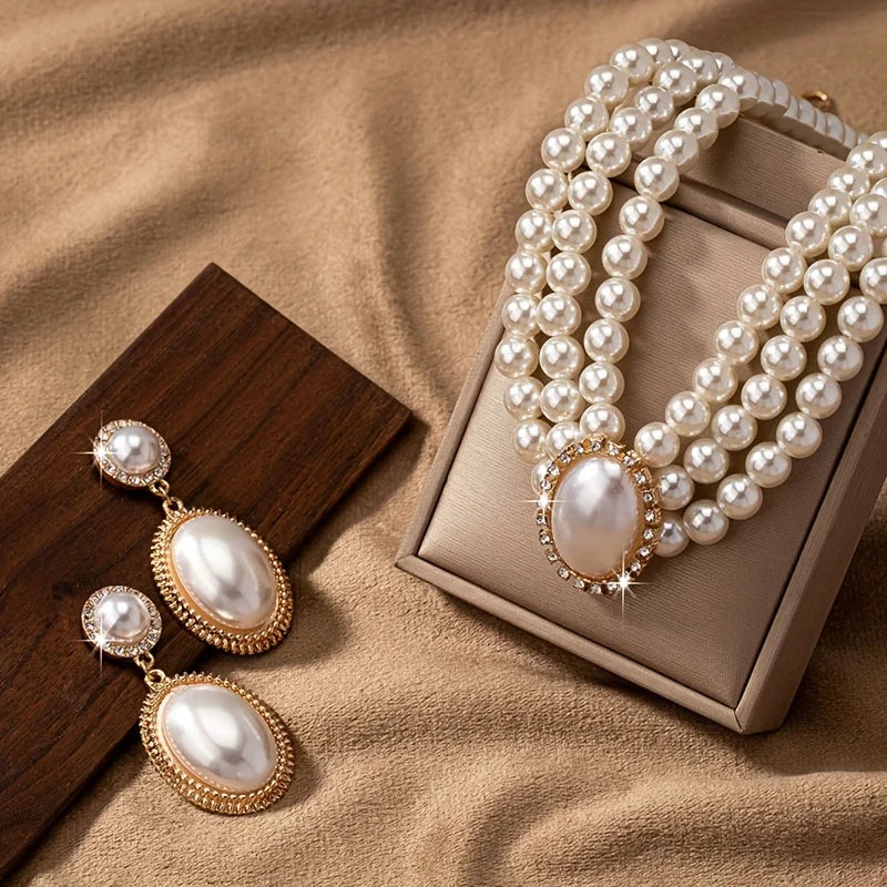 Elegant imitation pearl necklace and matching earrings set with gold accents, displayed on a white background.