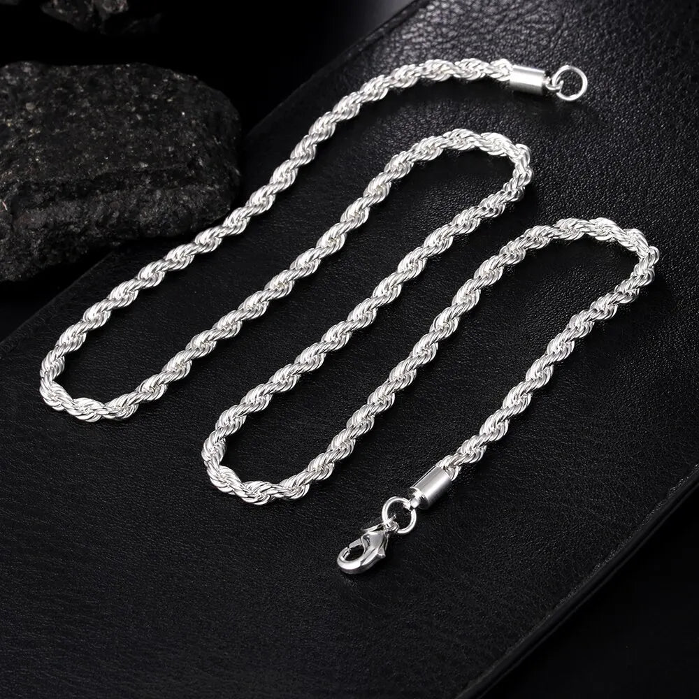 Silver 4mm men's braided cord chain necklace, 55cm and 20cm lengths, from Corporación Turística, displayed on a white background.