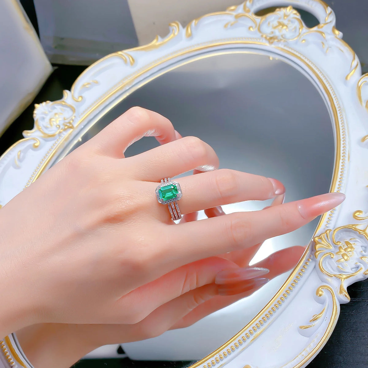 Elegant white platinum 18K luxury ring with green accents, crafted by Corporación Turística, showcased on a neutral background.
