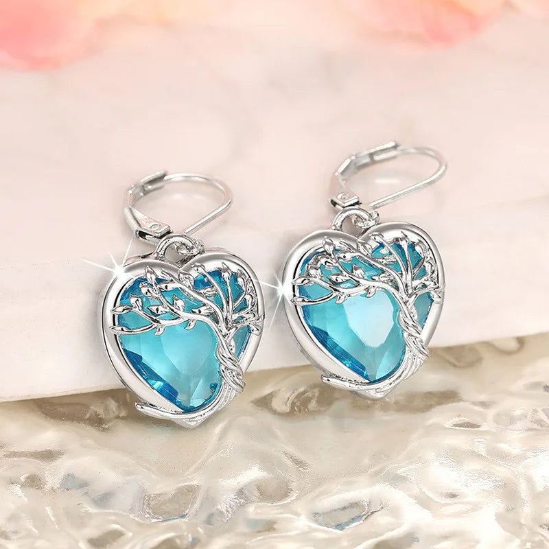 Blue crystal heart-shaped dangling earrings from Corporación Turística, featuring elegant, shimmering jewelry design.