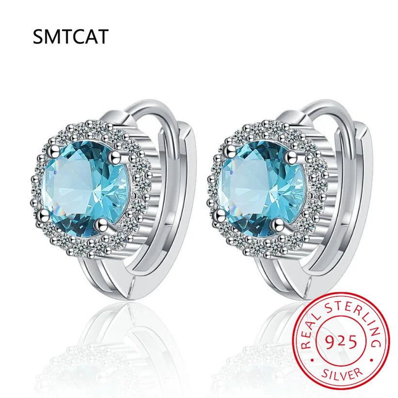 Silver 925 blue sapphire hoop earrings by Corporación Turística, showcasing elegant round hoops with vibrant blue gemstones.