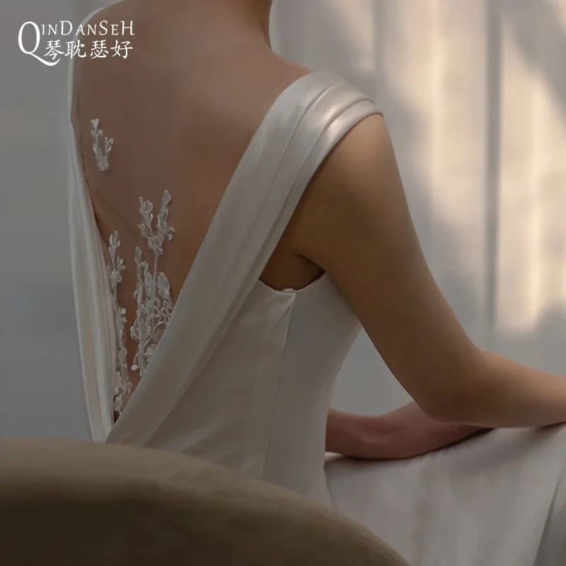 Lightweight backless wedding dress by Corporación Turística, elegant white bridal gown with flowing fabric and delicate design details.