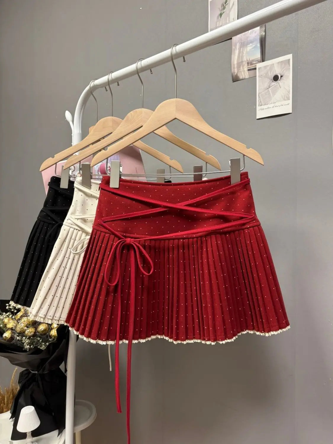 White pleated skirt with crisscross polka dot straps by Corporación Turística, showcasing the stylish design and fabric texture.