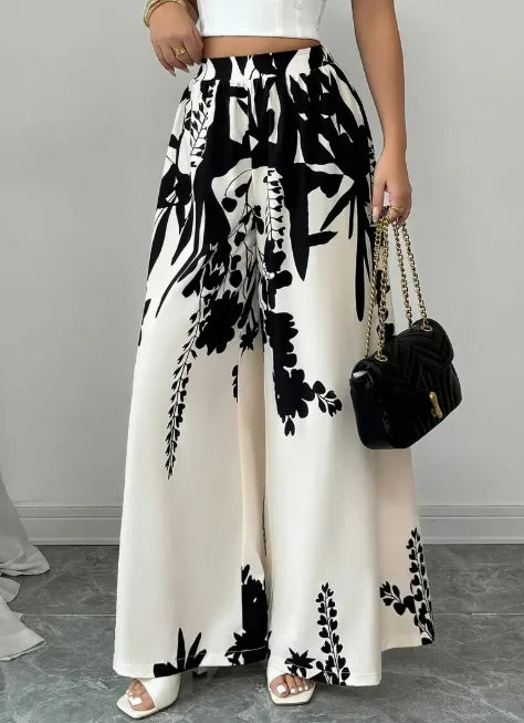 White silky floral print wide-leg pants from Corporación Turística, featuring a smooth satin fabric and comfortable fit.