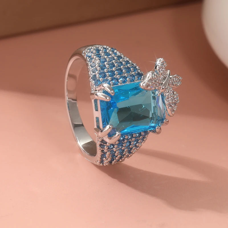 Elegant blue topaz cocktail ring by Butterfly featuring a detailed butterfly design and sparkling gemstone.