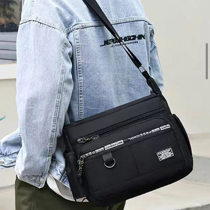 Black nylon men's shoulder bag with multiple layers, ideal for business travel, from Corporación Turística.