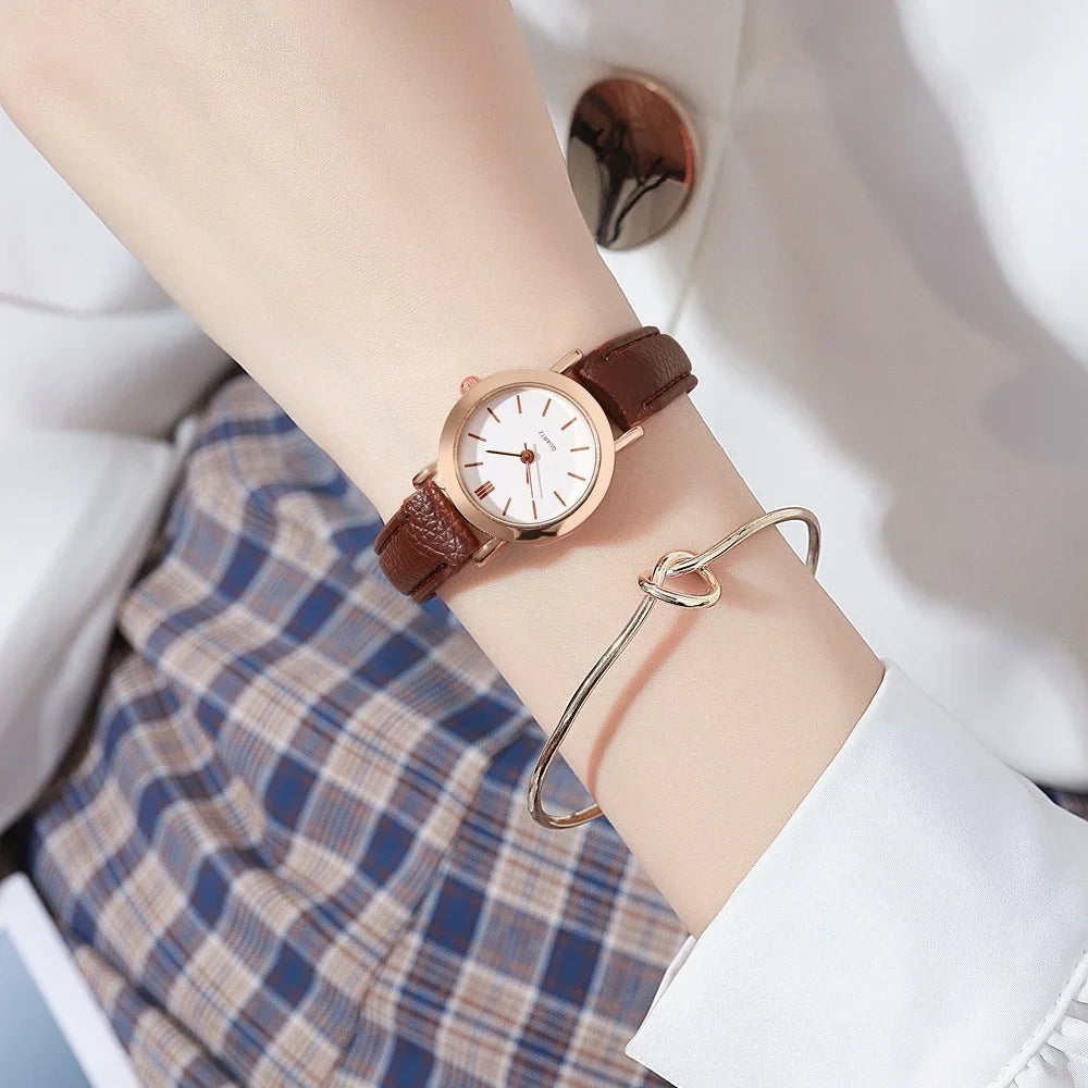 Minimalist women's quartz watch with white dial and brown strap by Corporación Turística, elegant and simple accessory.