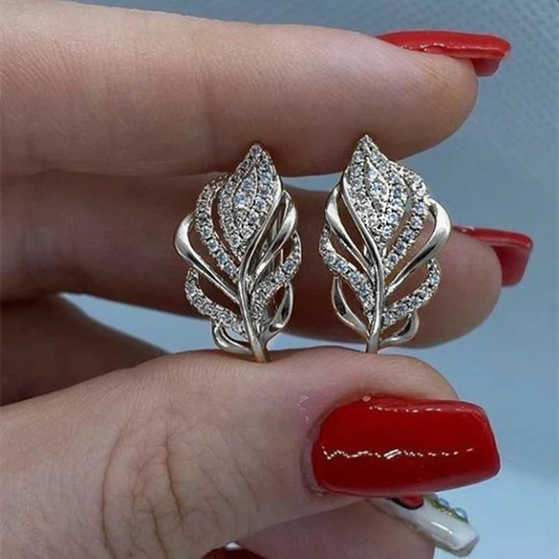 Silver hoop earrings with leaf-shaped design from Huitan by Corporación Turística, showcasing elegant and natural style.
