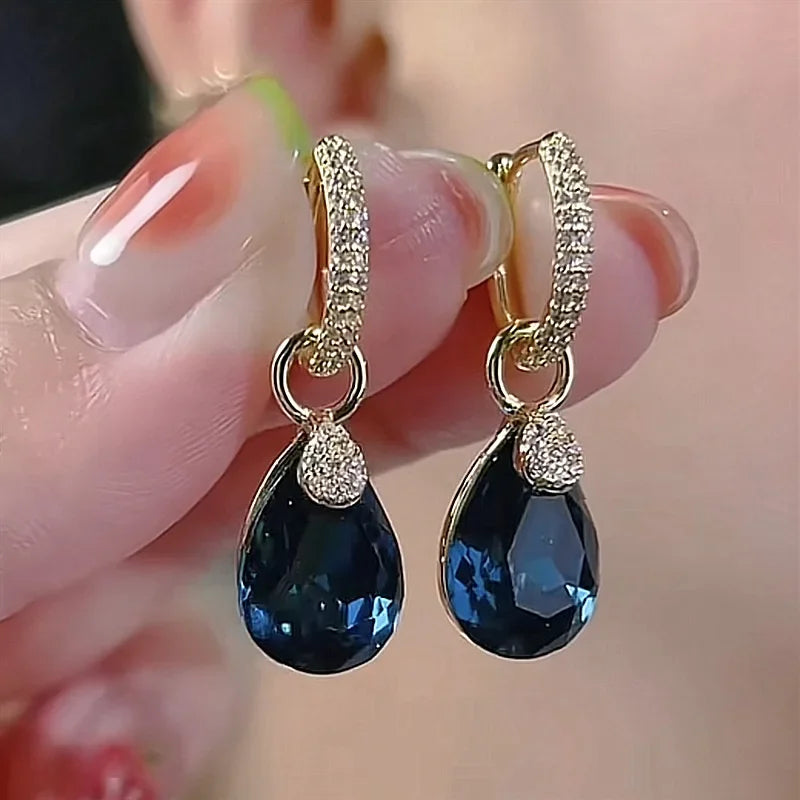 Exquisitos pendientes colgantes de cristal en forma de gota, con diseño elegante y transparente, de la marca Corporación Turística.