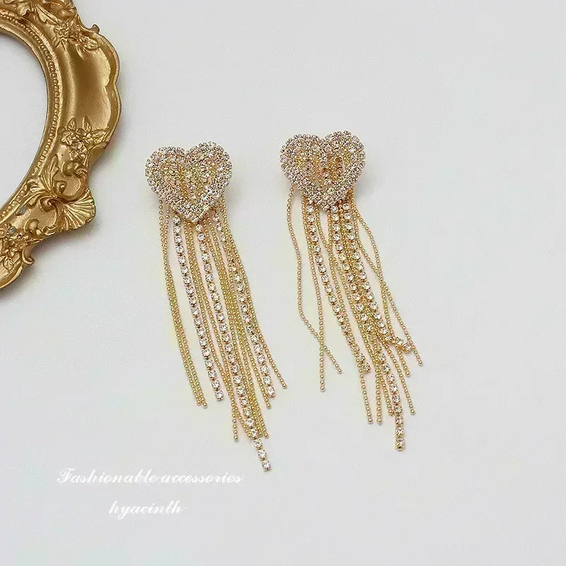 Exquisitos pendientes colgantes de cristal en forma de gota, diseñados por Corporación Turística, con acabado en color blanco.
