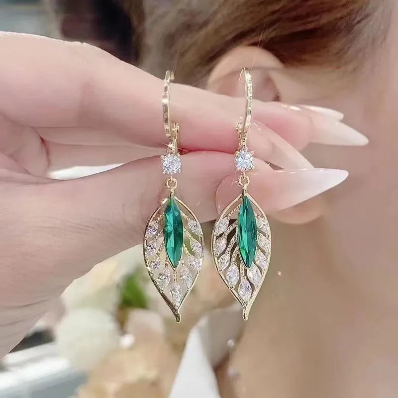 Gold leaf crystal earrings for women featuring green crystals, stylish dangling earrings with elegant leaf design.