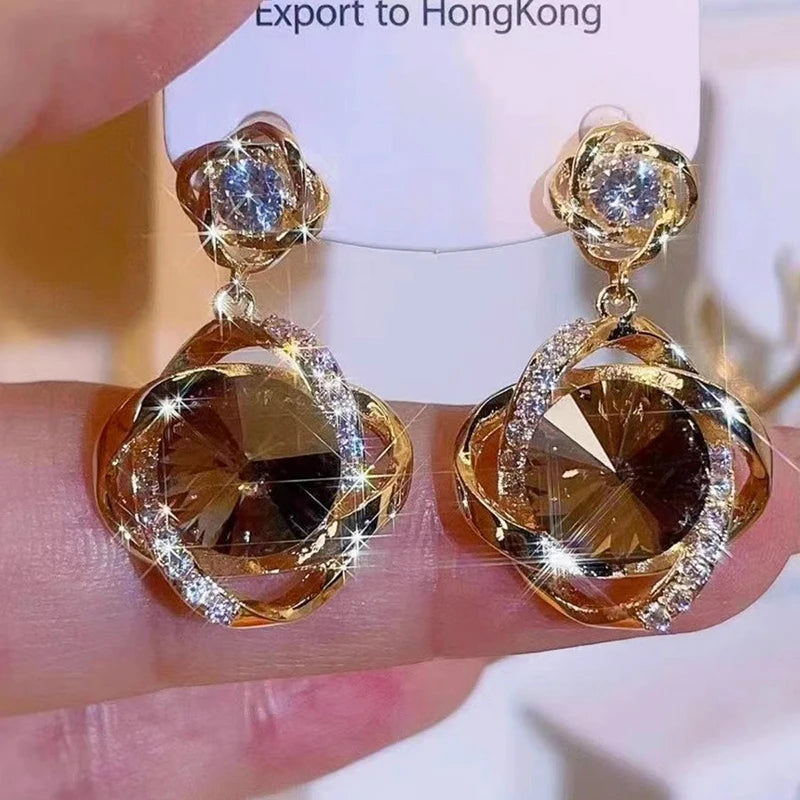 Elegant gold earrings with round crystal pendants wrapped in decorative wire, perfect for stylish accessories.