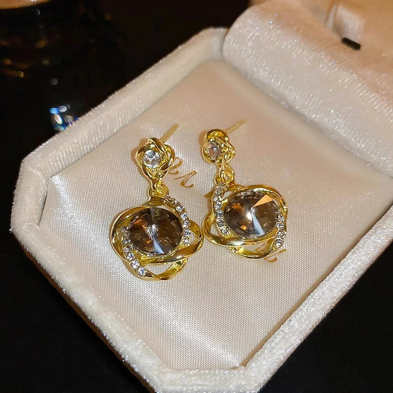 Gold-tone dangling earrings with round crystal pendants wrapped in decorative metal, elegant jewelry from Corporación Turística