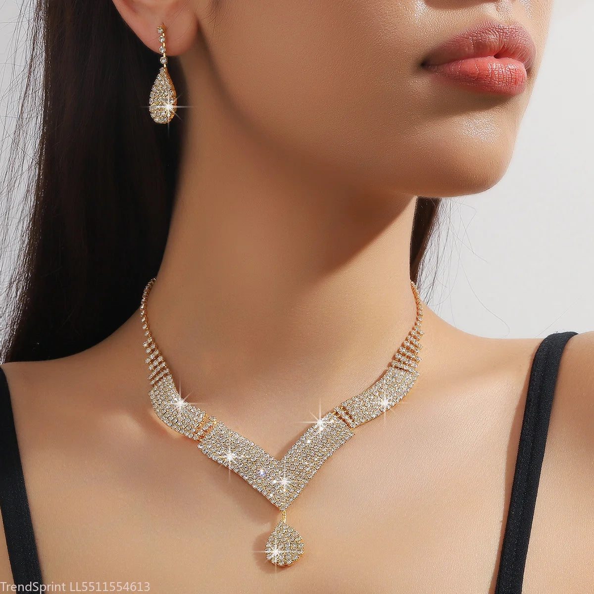 Fashion jewelry set with drop-shaped rhinestones featuring gold-tone finish, elegant earrings and necklace from Corporación Turística.