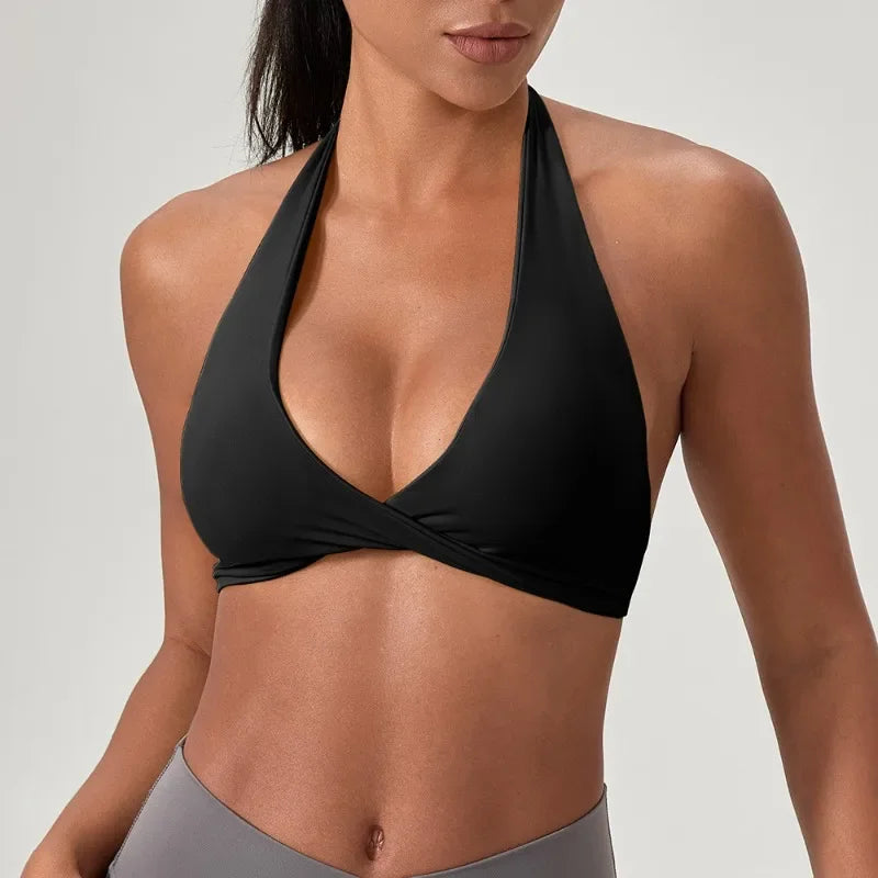 Black women's yoga sports bra with halter neck from Corporación Turística, shown on a model highlighting the design and fit.