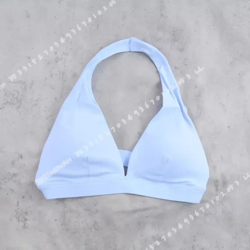 Light blue women's sports bra with halter neck design by Corporación Turística, shown on a white background.