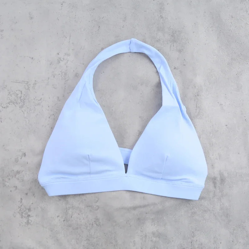 Light blue women's sports bra with halter neckline from Corporación Turística, designed for active wear.