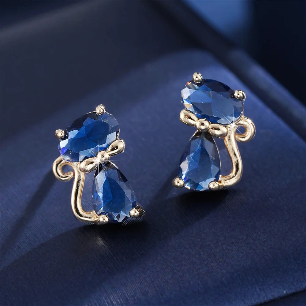 Small green cat-shaped earrings with zirconia stones, crafted by Corporación Turística, shown on a white background.