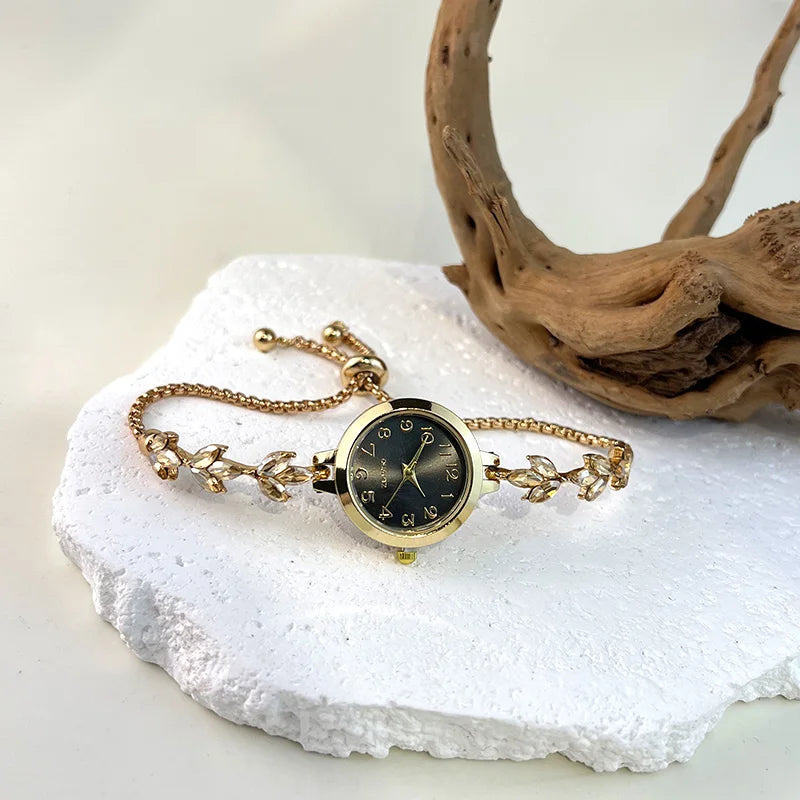 Elegant black and gold adjustable bracelet watch with a crystal cord, featuring a sleek design from Corporación Turística.