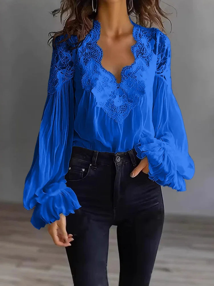 White lace blouse with deep V-neck and long sleeves, from Corporación Turística, shown on a hanger.