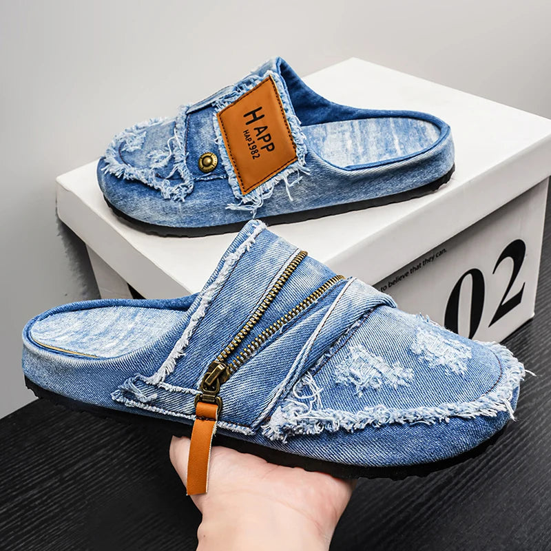 Light blue denim mules with frayed edges from Corporación Turística, featuring a casual slip-on design and textured fabric.