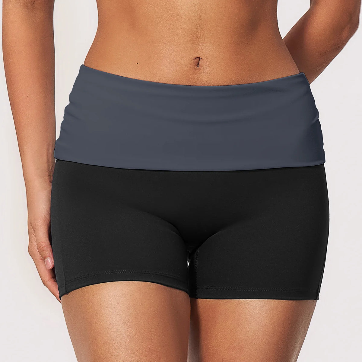 Navy blue women's yoga shorts with fold-over waistband and light effect, made by Corporación Turística, shown on a model.
