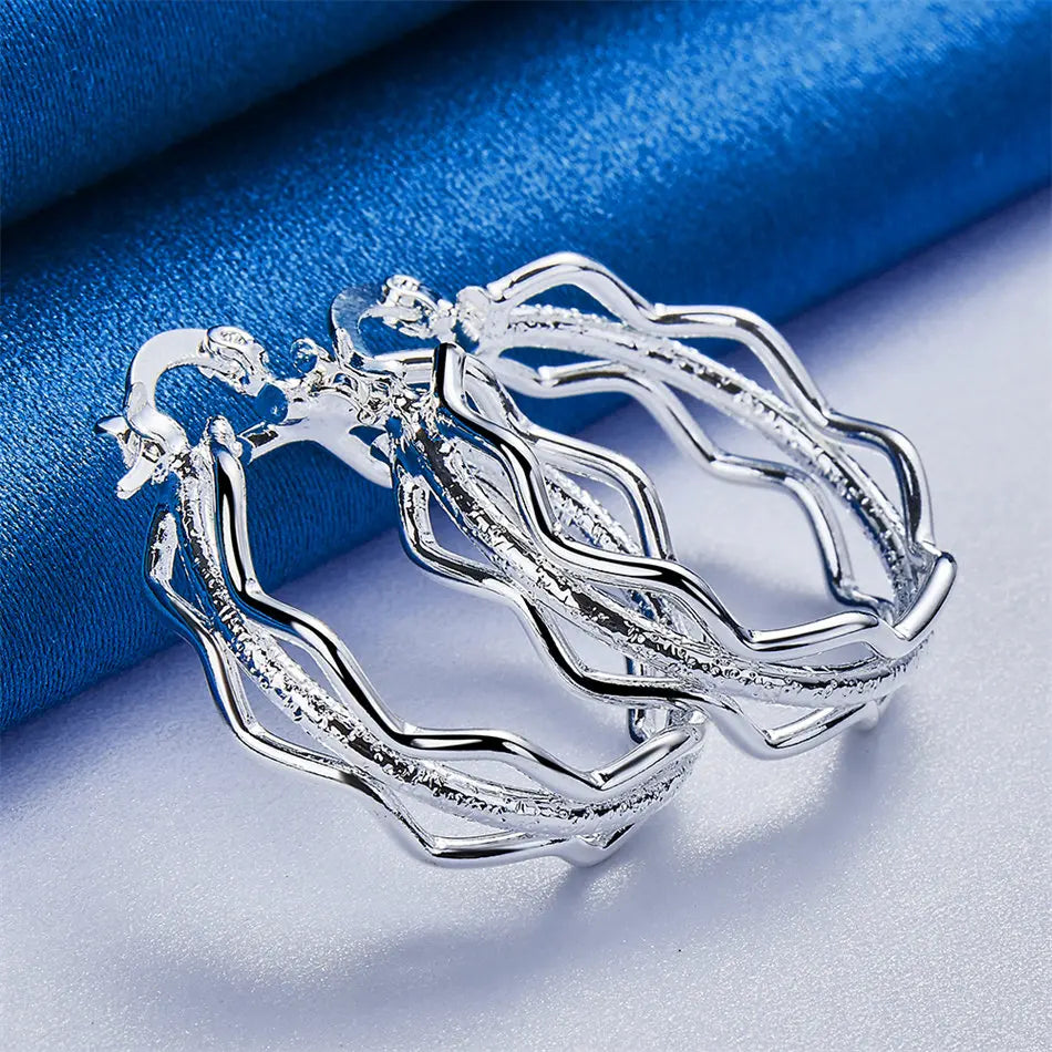 Sterling silver earrings with wave design from Corporación Turística, featuring elegant flowing curves and polished finish.