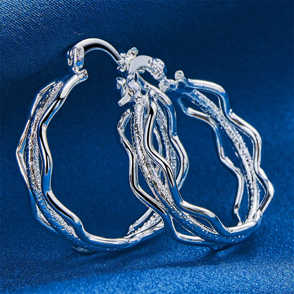 Sterling silver earrings with wave design by Corporación Turística, showcasing elegant, handcrafted silver jewelry with wave-shaped details.