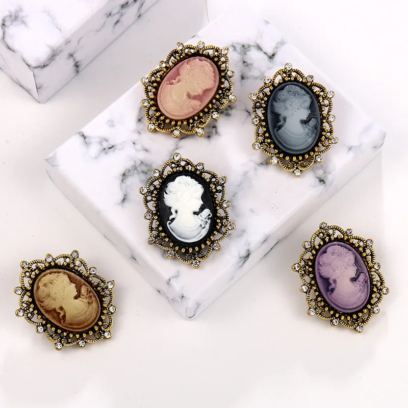 Vint-style queen cameo brooch with imitation diamonds, featuring purple tones and intricate design, by Corporación Turística.