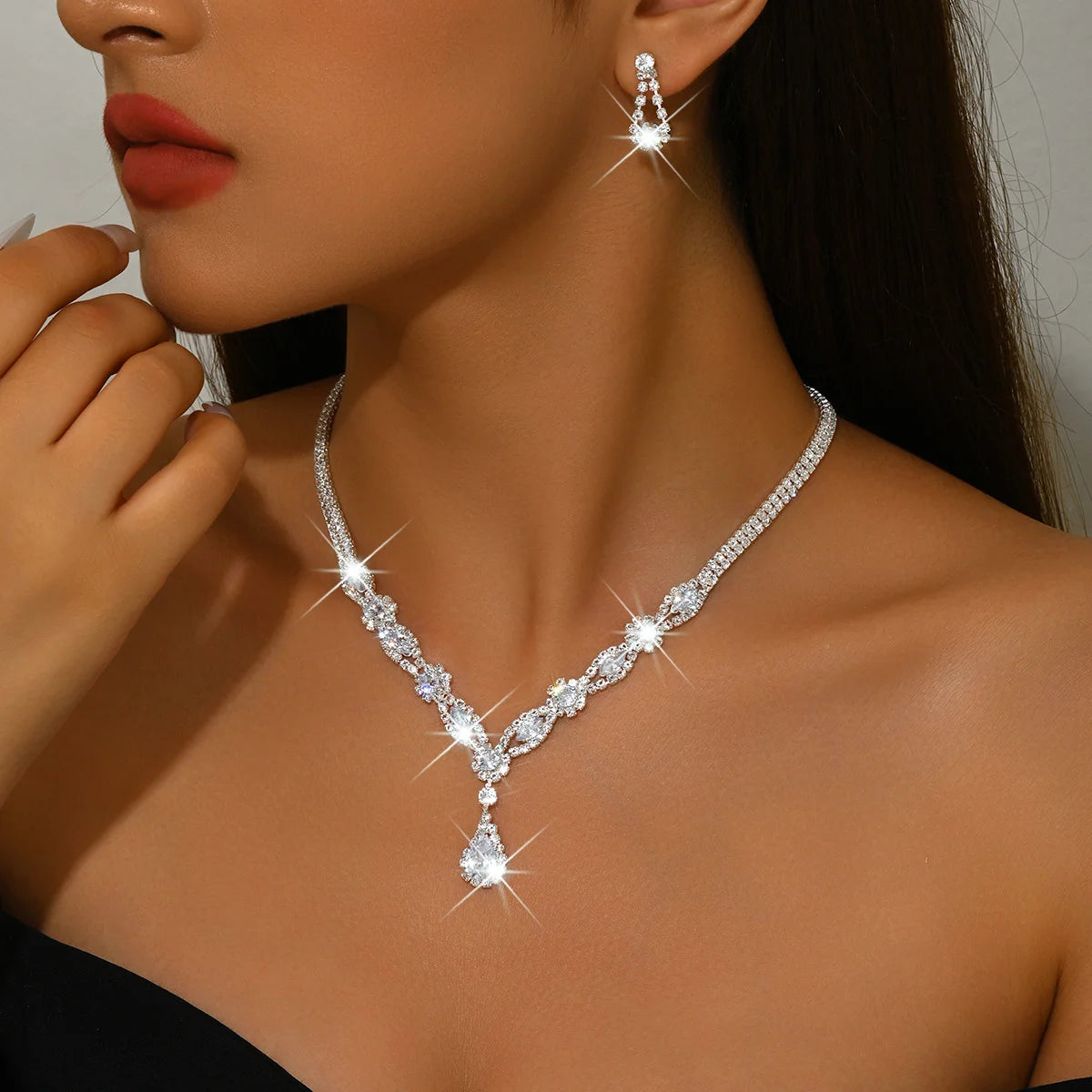 Luxury silver crystal jewelry set featuring elegant shapes, includes necklace, earrings, and bracelet with intricate design.