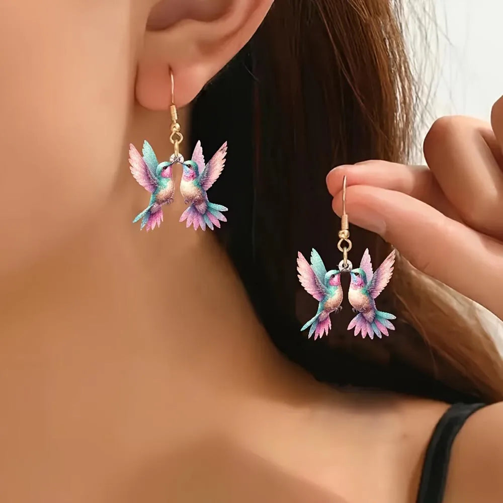Acrílicos pendientes de colibrí de Corporación Turística, con forma de colibrí en colores vibrantes, sobre un fondo neutro.