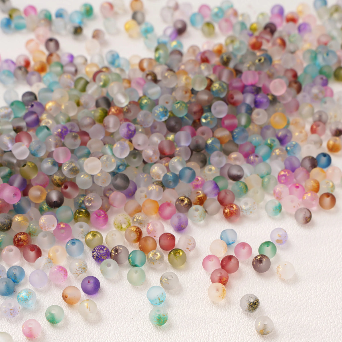 Set of 100 gold-splashed glass rice beads by Corporación Turística, 4mm, featuring shiny, decorative glass beads for jewelry making.