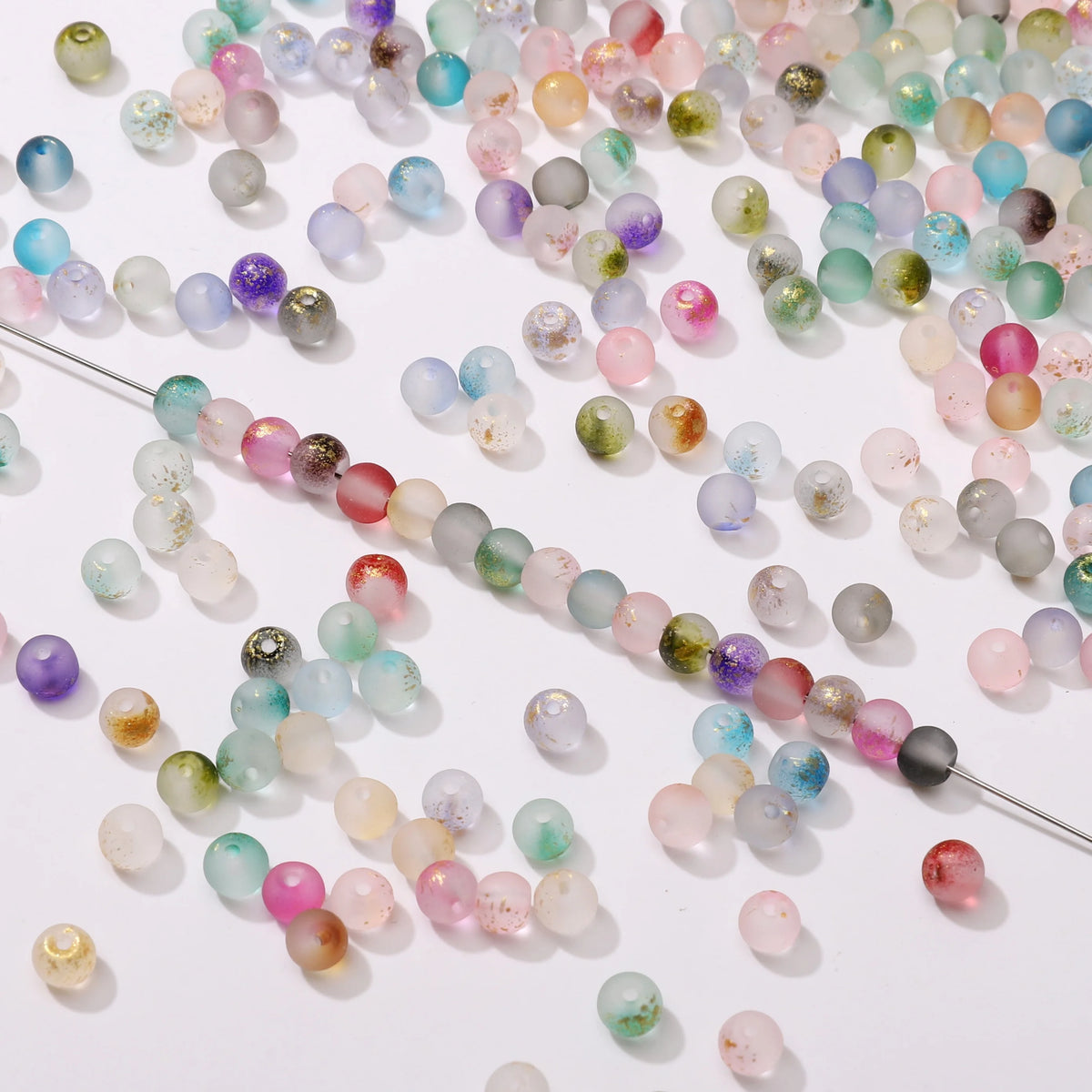 Set of 100 gold-splashed glass rice beads from Corporación Turística, 4mm, ideal for jewelry making and craft projects.