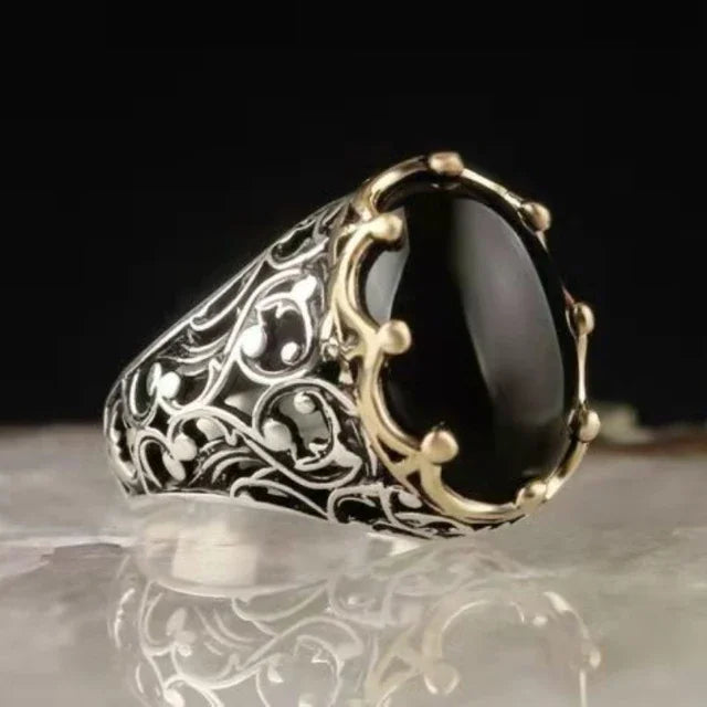 Luxury emerald ring with intricate inlays, featuring a prominent green emerald gemstone and detailed craftsmanship.