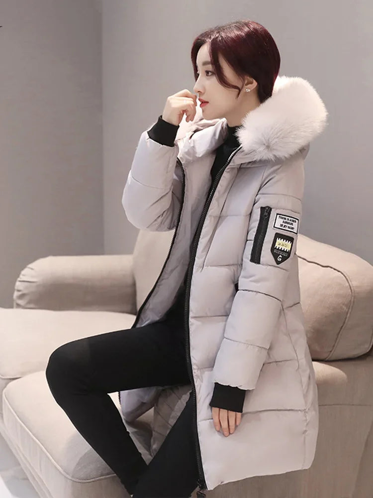 Long black winter coat for women with hood and high collar by Corporación Turística, shown on a model.