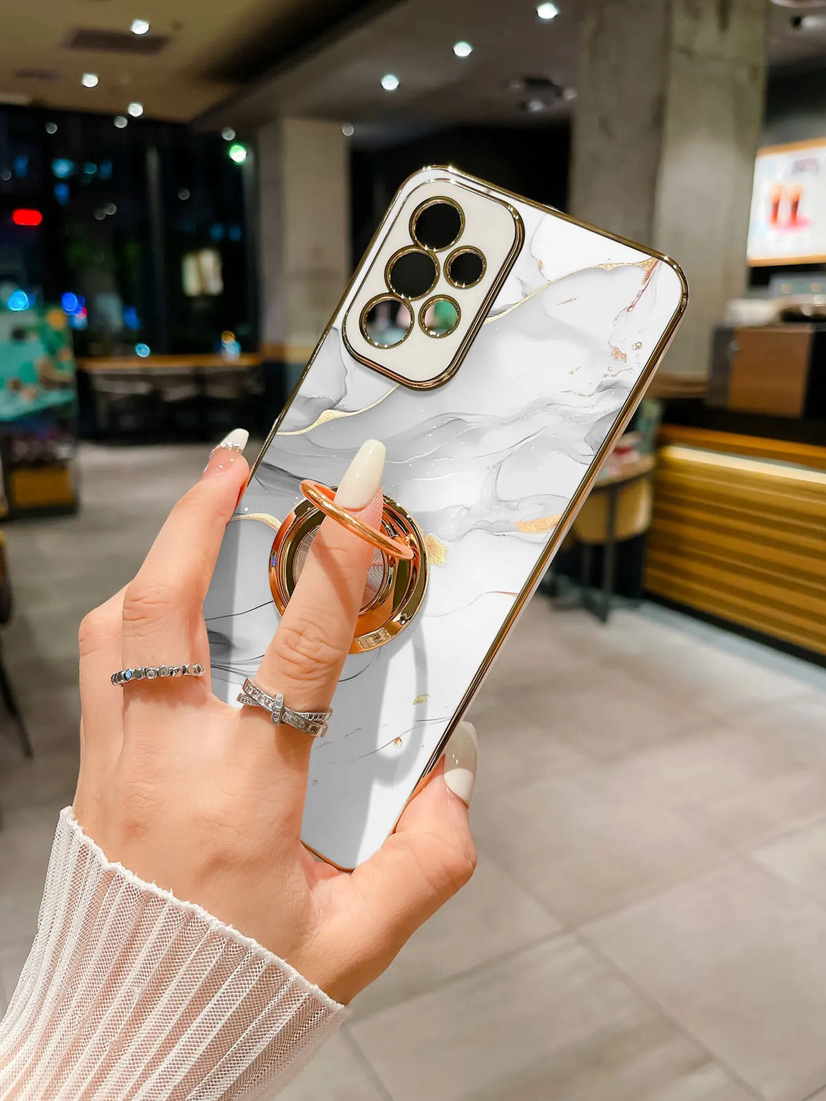 Phone case with ring stand featuring a marble pattern, designed by Corporación Turística, shown on a smartphone.