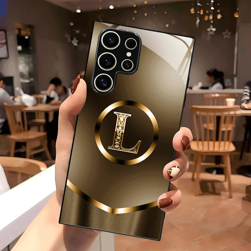 Black glass phone case with the letter L from Corporación Turística, elegant and sleek design, shown on a smartphone.