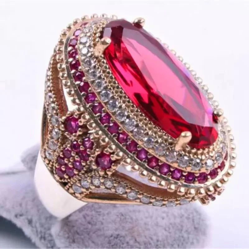 Red cubic zirconia ring with oval inlays from Corporación Turística, featuring a sparkling gemstone design and intricate metalwork.