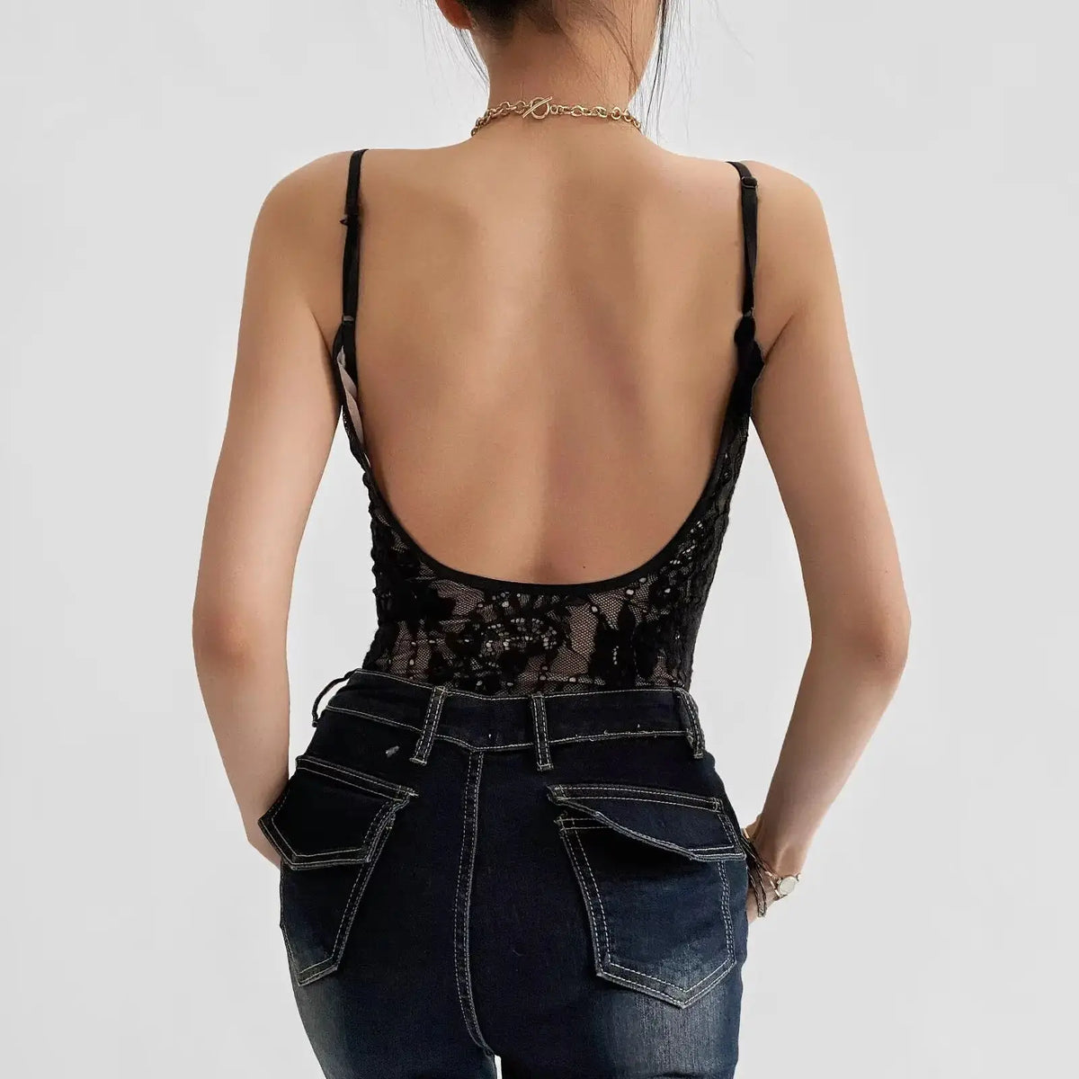 Sexy transparent lace backless bodysuit with lining, styled by Corporación Turística, shown in black on a model.