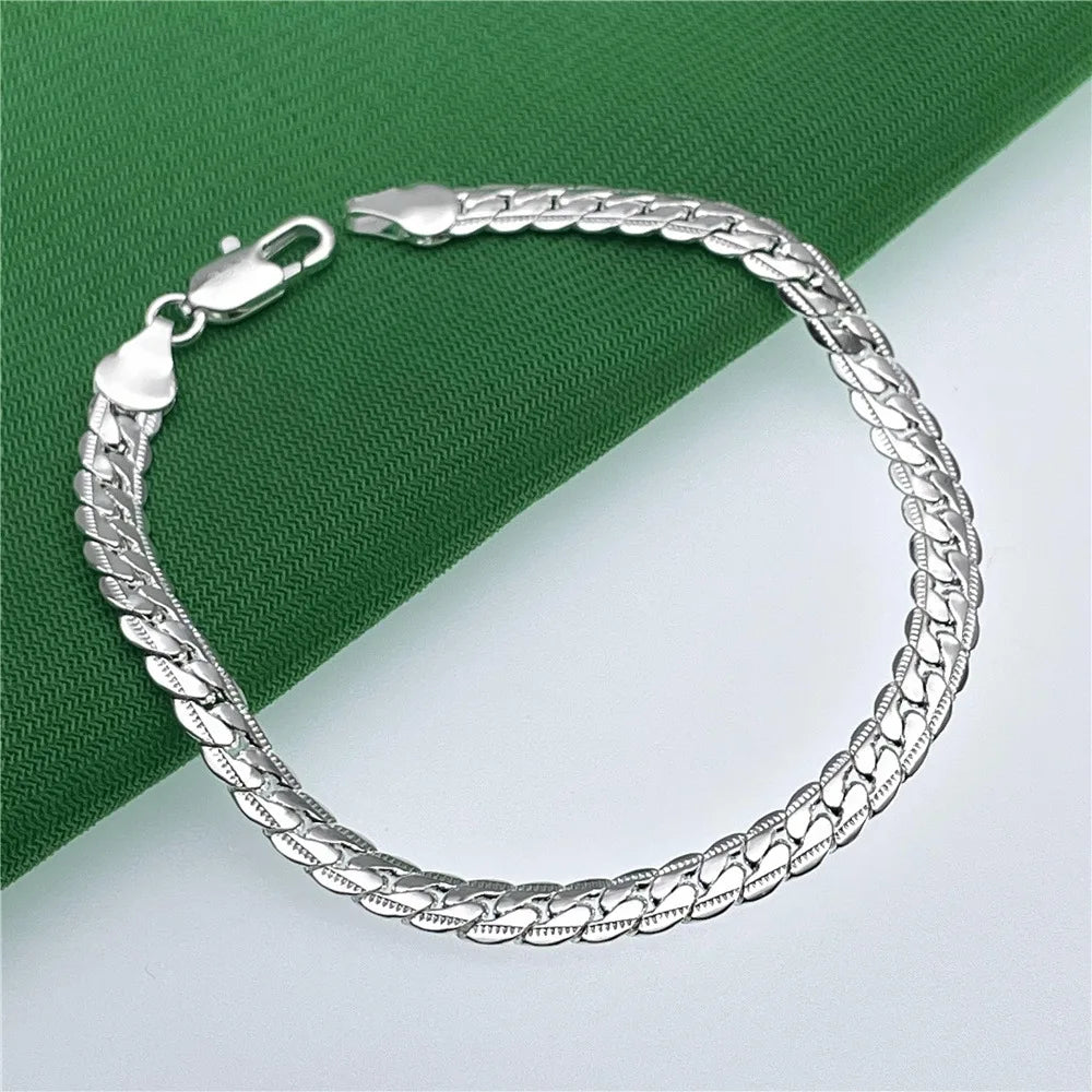 Sterling silver 925 bracelets for women and men, featuring sleek and modern designs, worn on wrists in a stylish setting.