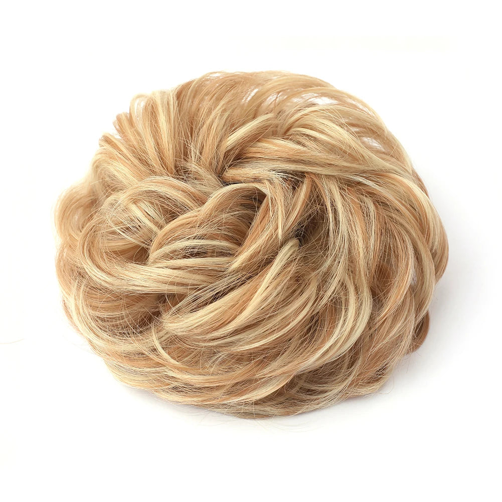 Large messy bun with wavy and curly hair, styled by Corporación Turística, showcasing a casual, tousled hairpiece.