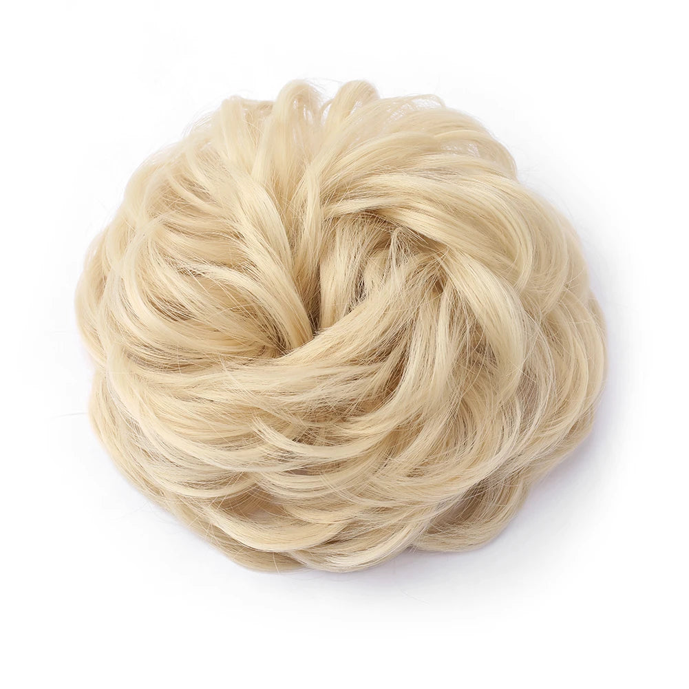 Large messy bun with wavy, curly hair piece from Corporación Turística, showcasing textured, voluminous hairstyle.