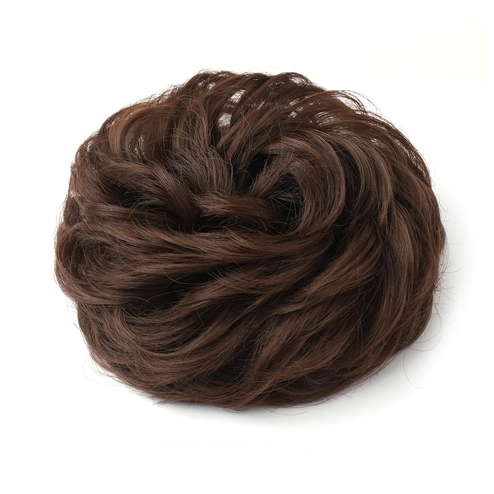 Large messy bun hairstyle with wavy and curly hair, styled by Corporación Turística, featuring a voluminous, tousled updo.