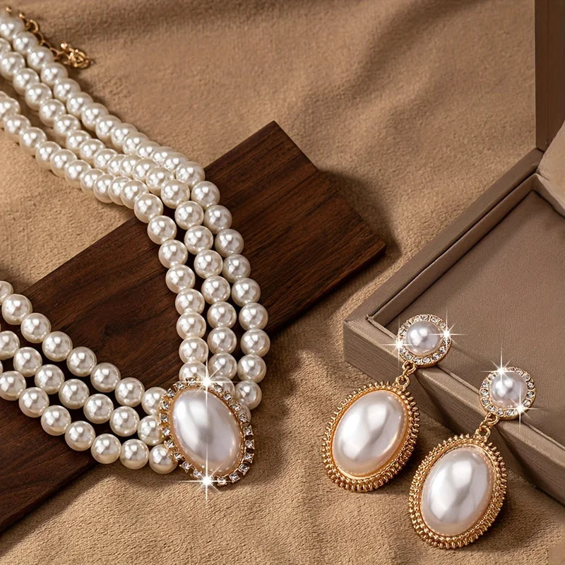Set of elegant imitation pearl necklace and matching earrings, showcasing shiny white pearls and silver hooks.