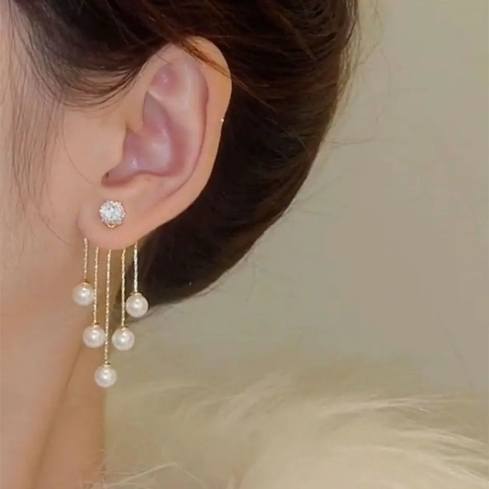 Korean fashion pearl tassel earrings with needle, white pearl beads, stylish jewelry by Corporación Turística on a white background.