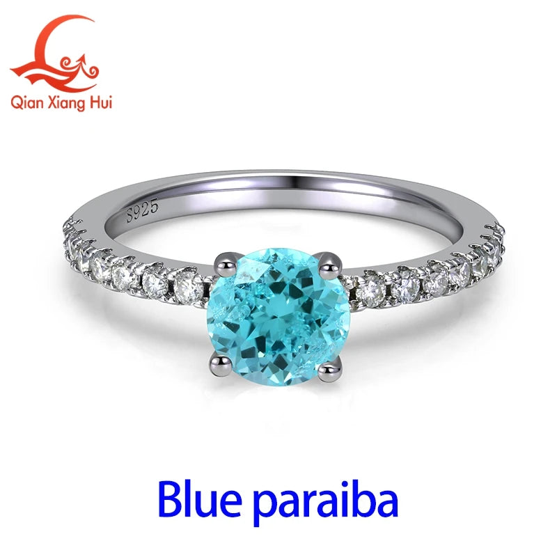 Silver ring featuring a 6.5mm neon blue Paraiba tourmaline with greenish hue, set in a YAG gemstone design.