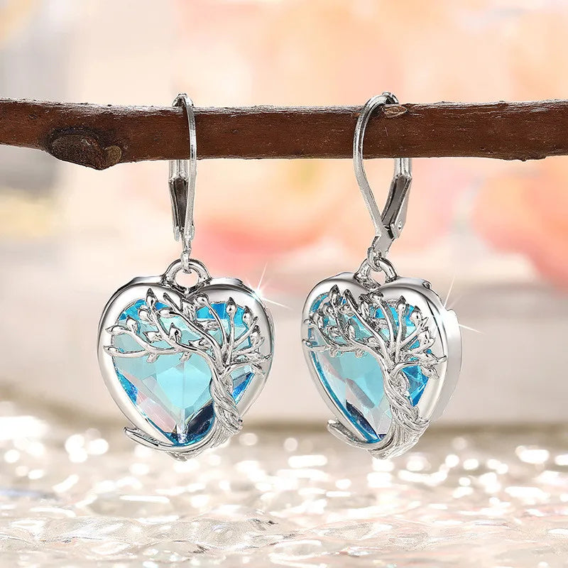 Blue crystal heart-shaped pendant earrings from Corporación Turística, with elegant dangling design and sparkling gemstone accents.