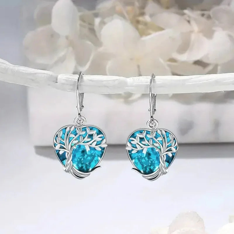 Blue crystal heart-shaped dangling earrings from Corporación Turística, elegant jewelry with shimmering gemstone details.